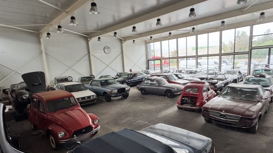 Oldtimerhal van JW Motors in Deurne met klassieke wagens, onder meer een rode Citroën 2CV, een Fiat 500 en een Mercedes SL