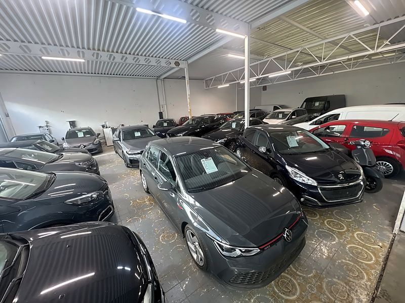 JW Motors showroom in Deurne: indoor showroom with used cars, a grey Volkswagen Golf GTI in front